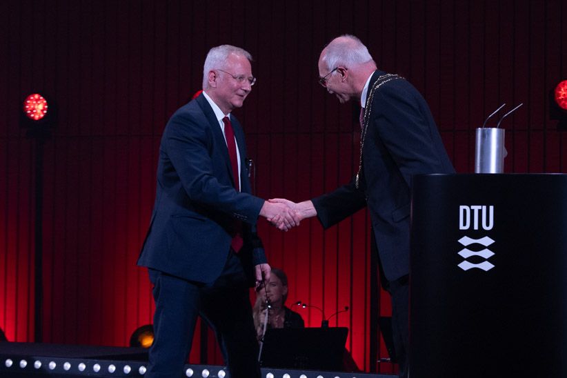 two men shaking hands at a podium with the words dtu
