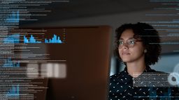 Female wearing glasses with computer and overlayed with graphs and data.