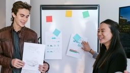 Two students presenting their plan on a whiteboard