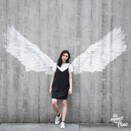 girl standing in front of painted wings on wall