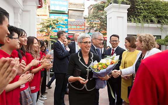 The Governor of Victoria greets people at the Swinburne Vietnam opening in Hanoi, holding a bouquet of flowers