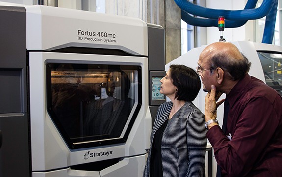 People inspect a 3D printer within the Factory of the Future