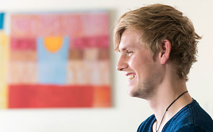 Image of a student in a student accommodation room with artwork in the background
