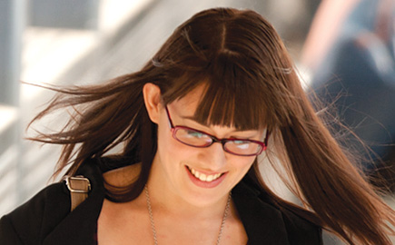 Image of female student wearing glasses with her hair blowing in the wind