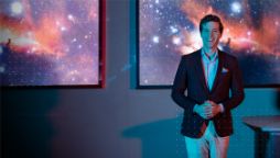 Professor Alan R Duffy, Swinburne astronomer and Director of the Space Technology and Industry Institute standing in front of an abstract galaxy background.