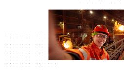 White background with a dotted overlay and image of a female student wearing safety clothing and equipment, taking a selfie in an industrial factory.