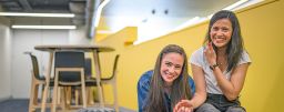  2 students sitting together looking at phone and smiling in Swinburne late lab