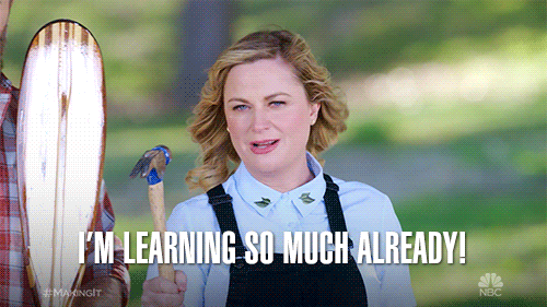Blonde woman in overalls holding a hammer with a white caption that reads 'I'm learning so much already'