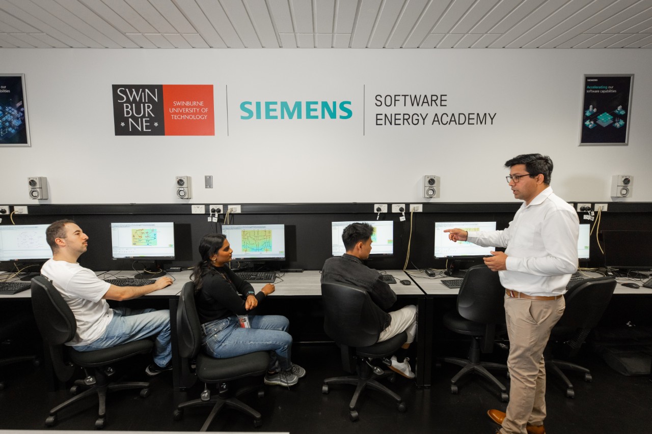 Students sitting at computers being shown how to use PSSE Software by a teacher
