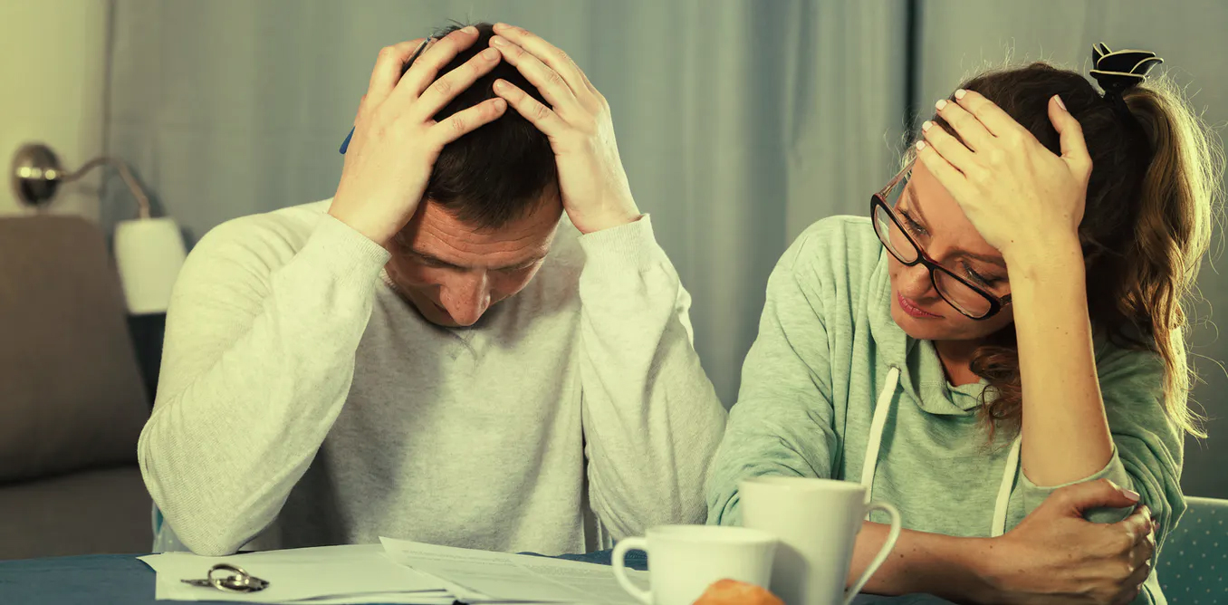 Man and woman appearing stressed while looking at paperwork