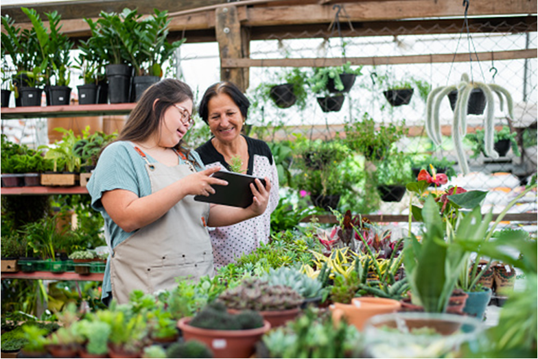 two women working inthe greenhouse, a worker with a disability and her supervisor