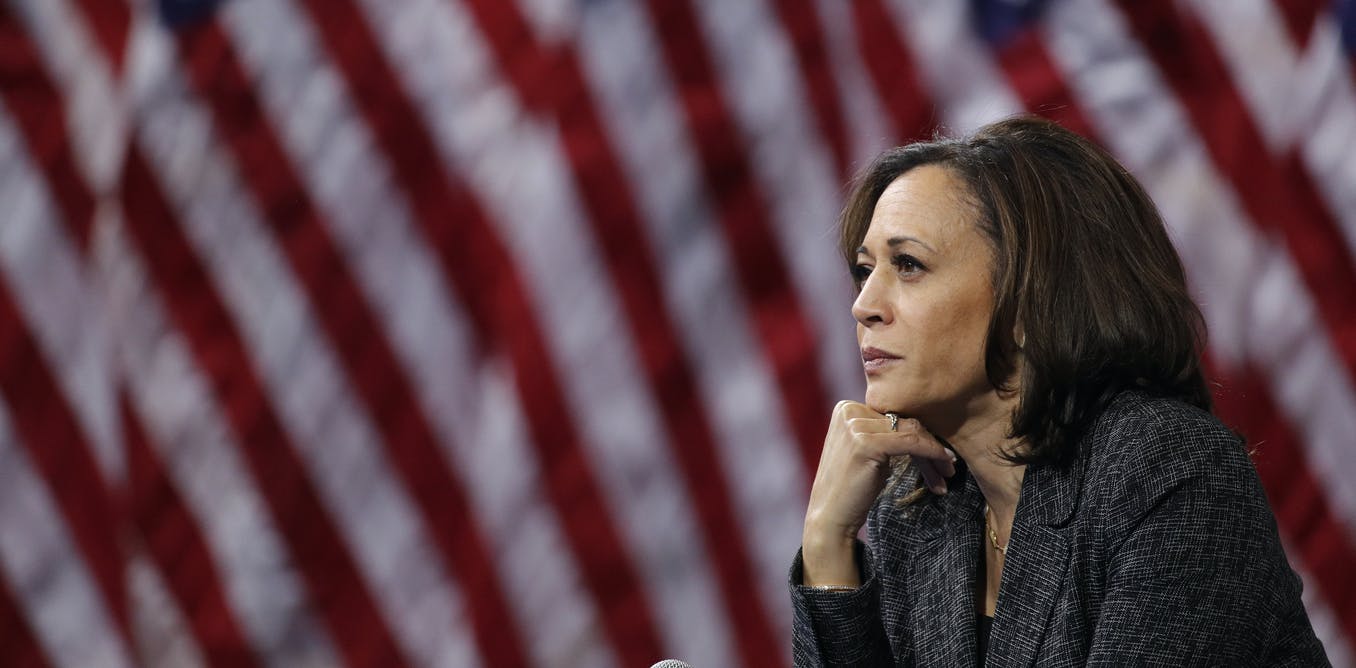 Vice-presidential nominee, Kamala Harris posing in front of a back-drop of American flags