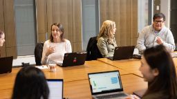 A group of females and males discussing with their laptops on the table in a meeting room setting.    LDI-learning-and-instructional-design