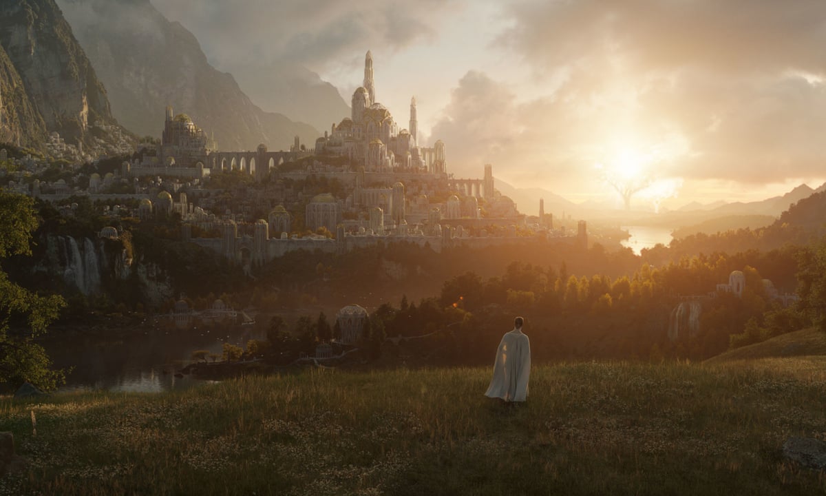A figure dressed in white is visible on a hill overlooking a middle earth castle at twilight