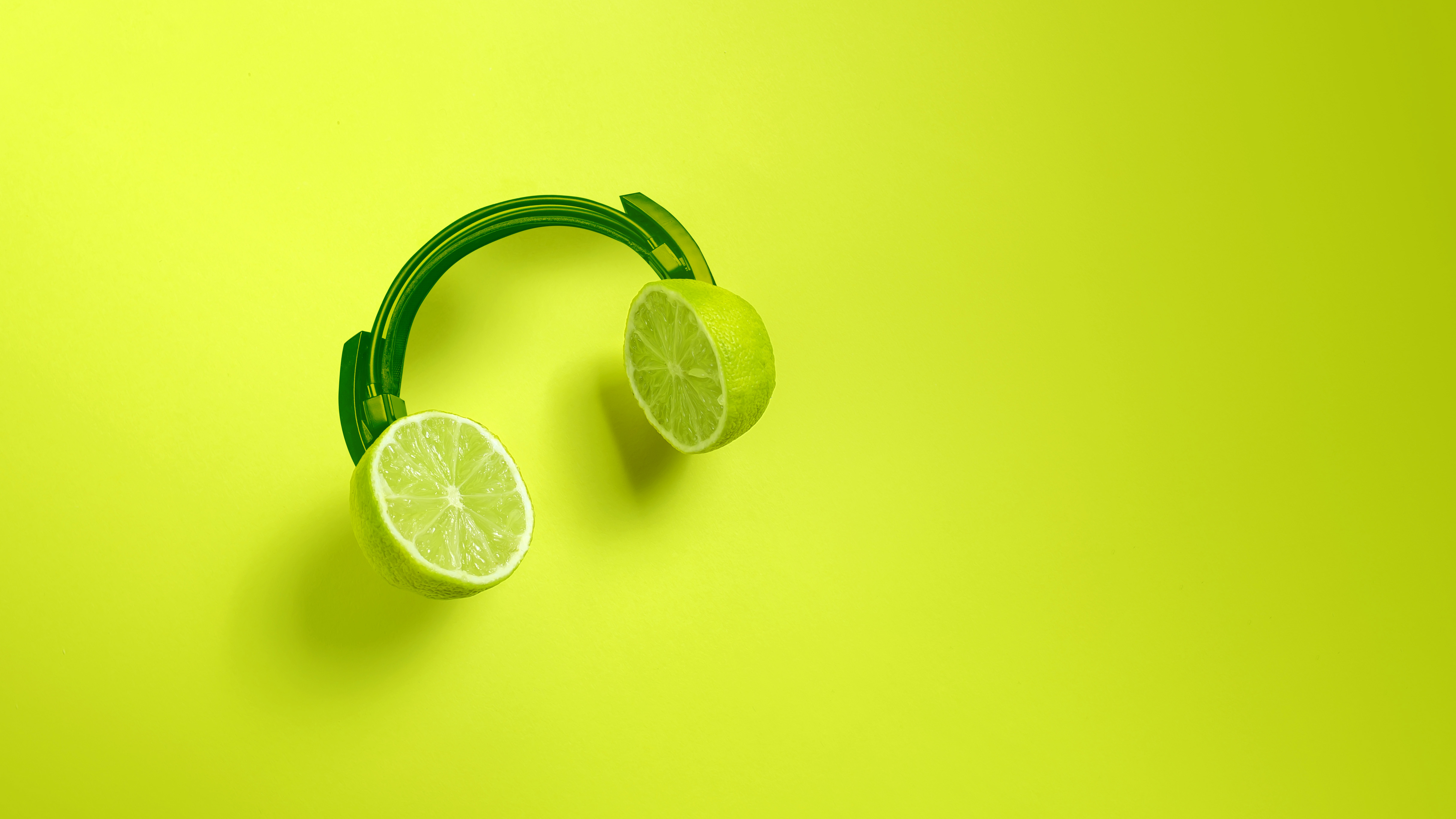 Green headphones with limes as the earpieces on a green background.