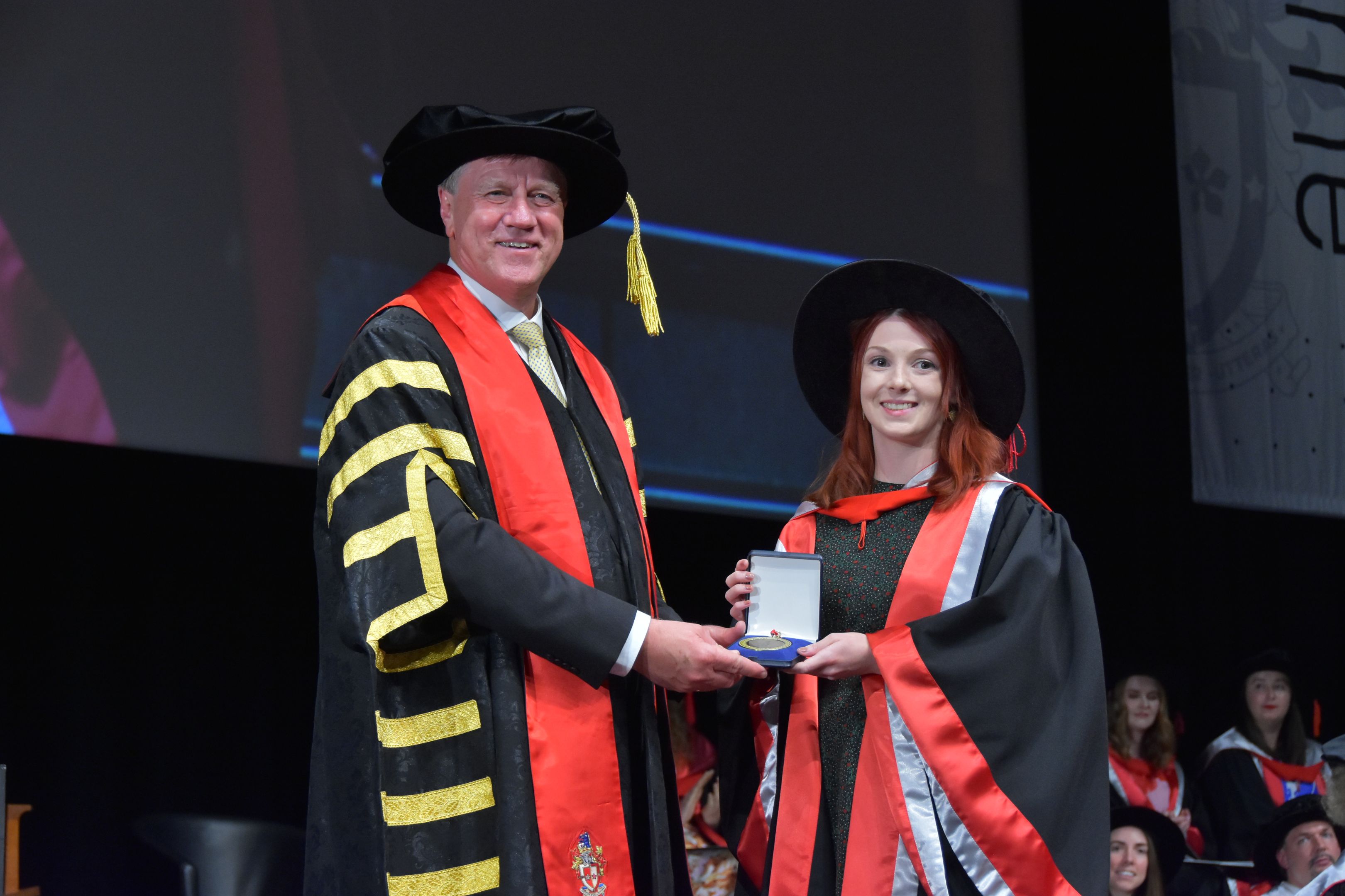 Recipient of the 2022 University Medal Dr Stephanie Harkin shaking hands with Swinburne Chancellor John Pollaers