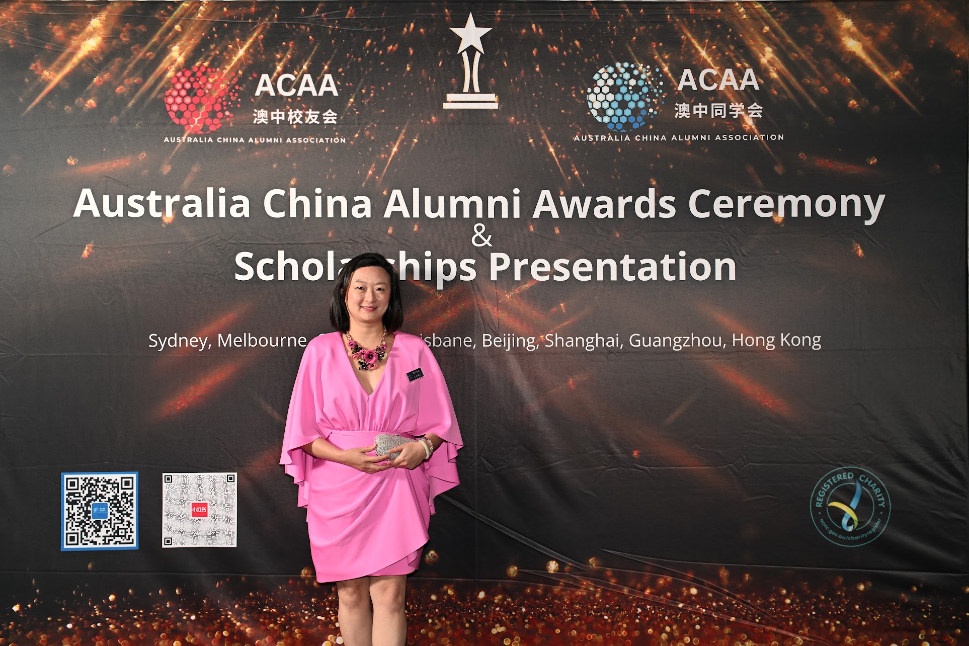 Woman in pink dress standing in front of ACAA sign