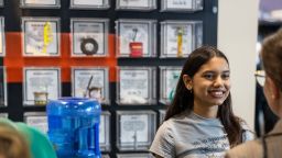 Young girl standing next to a water tank talking to someone at the cop expo