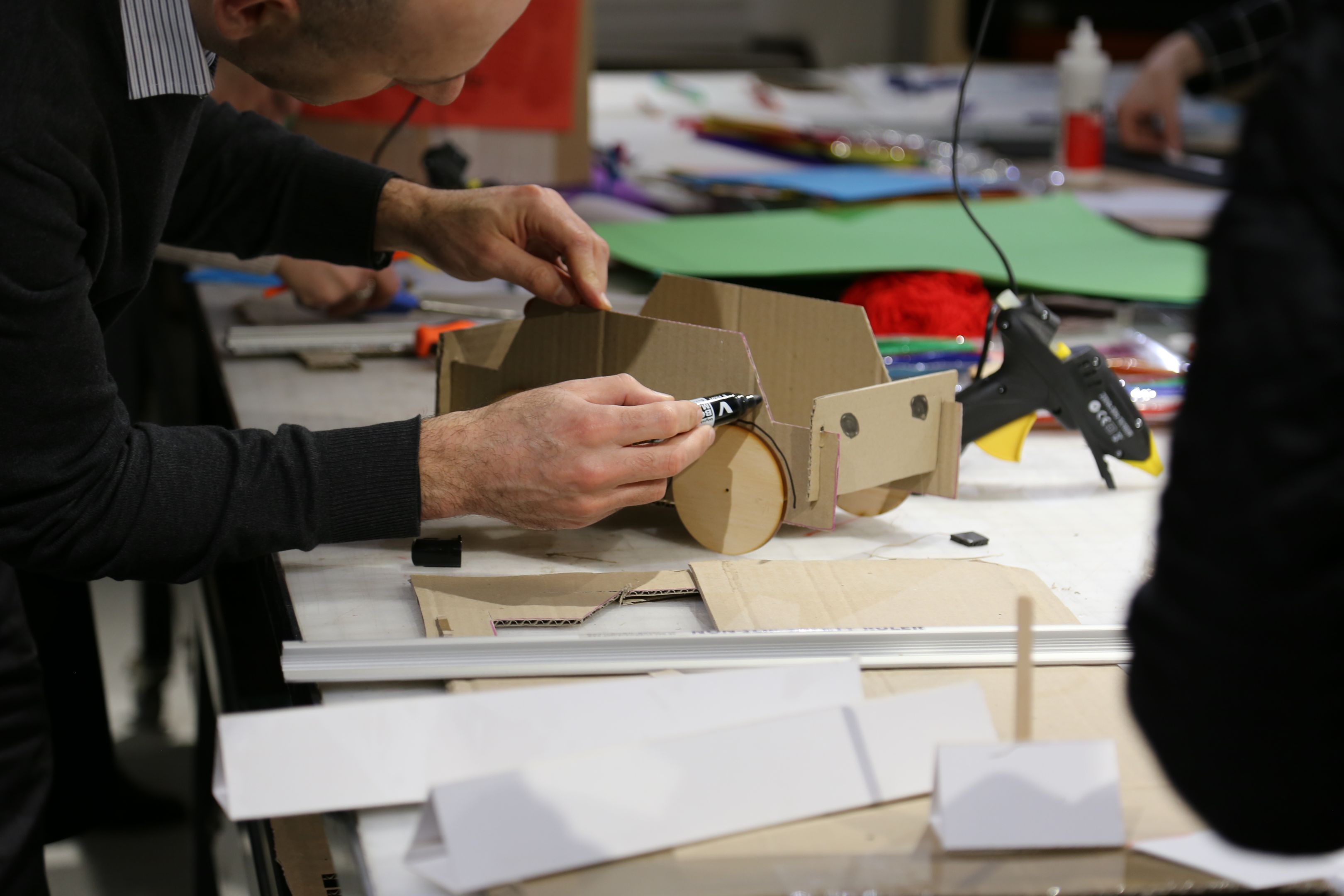 A close shot of hands working on a cardboard model. 