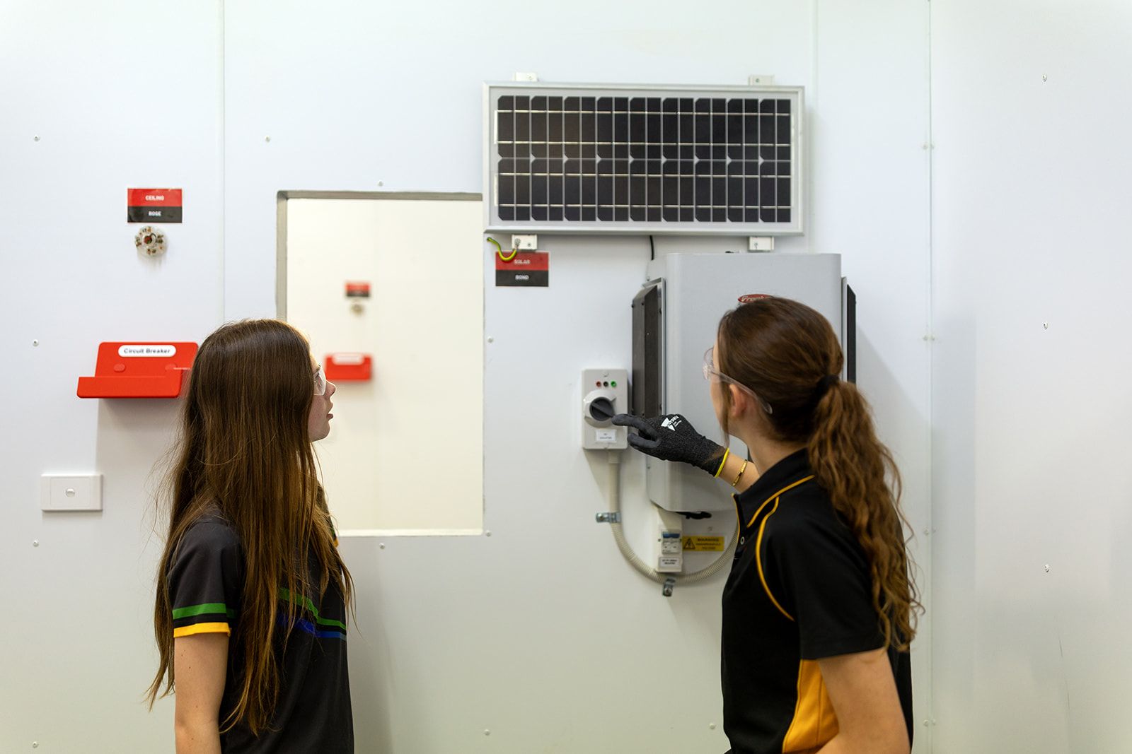 Two high school students looking at a circuit breaker