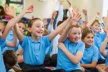 Excited School Children in Uniform with Hands Up