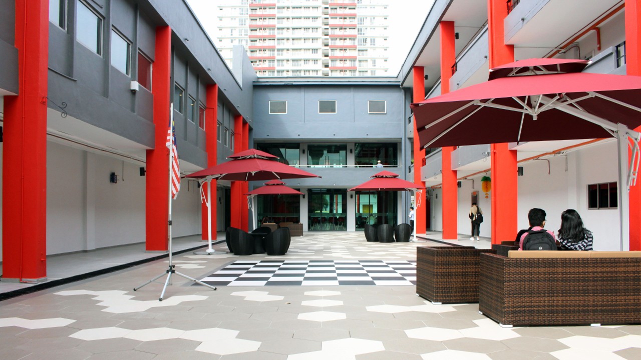 An outdoor courtyard with a painted chess board floor and seating area.