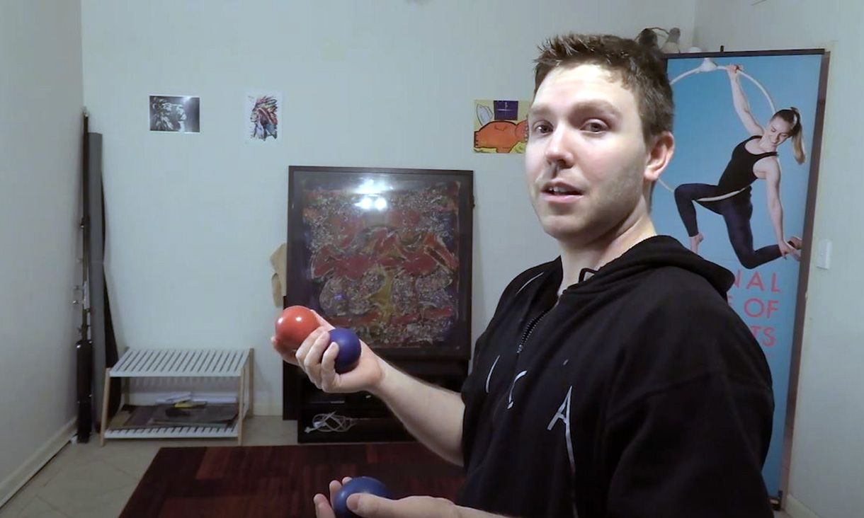 Man holding three juggling balls indoors