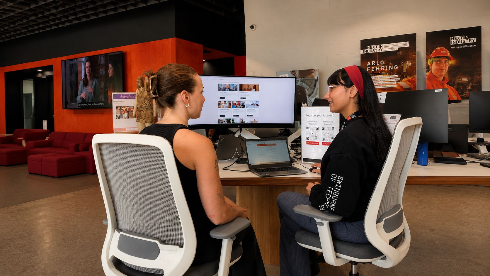 Two people sitting at a desk talking