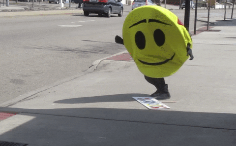 A spruiker in a smiley face suit falls over trying to pick up their spruiking sign
