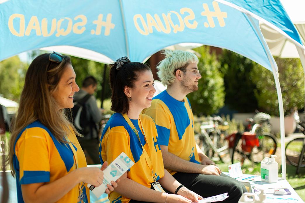 Students dressed in yellow and blue hand out R U OK Day promotions in a booth on Swinburne campus.