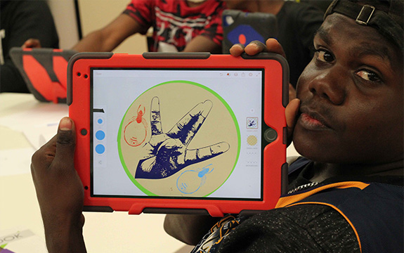 Ntaria senior student Marley Kantawarra holds up one of his digital drawings on the iPad
