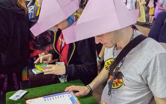 People wearing paper hats and playing a video game. 