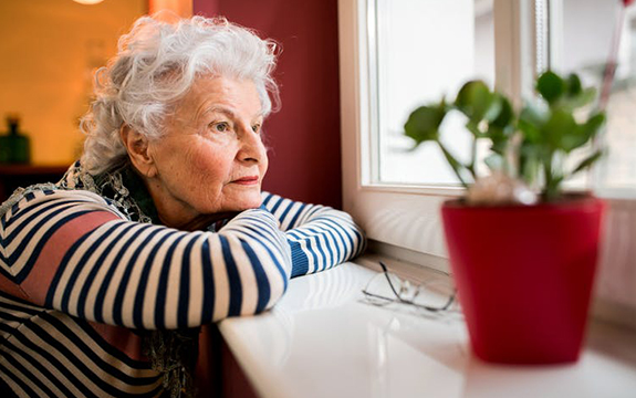 Older woman looking out of the window from inside a building