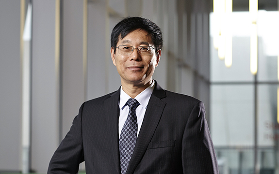 Professor Qing Long Han smiling in suit attire