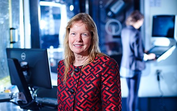 Dr. Leonie Walsh stands in front of blurred science lab equipment