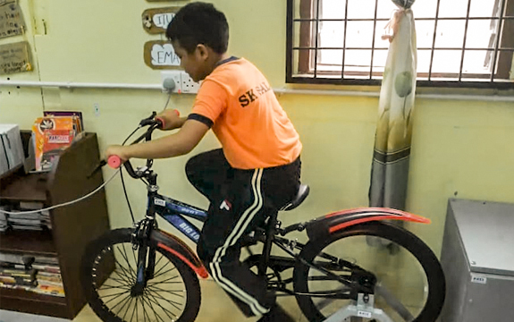 Children power a generator connected to outdoor lights with pedal power