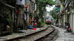 Train crossing the middle of Hanoi city with crowded houses