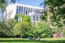 3 students sitting in Central Gardens with view of Swinburne building in background.