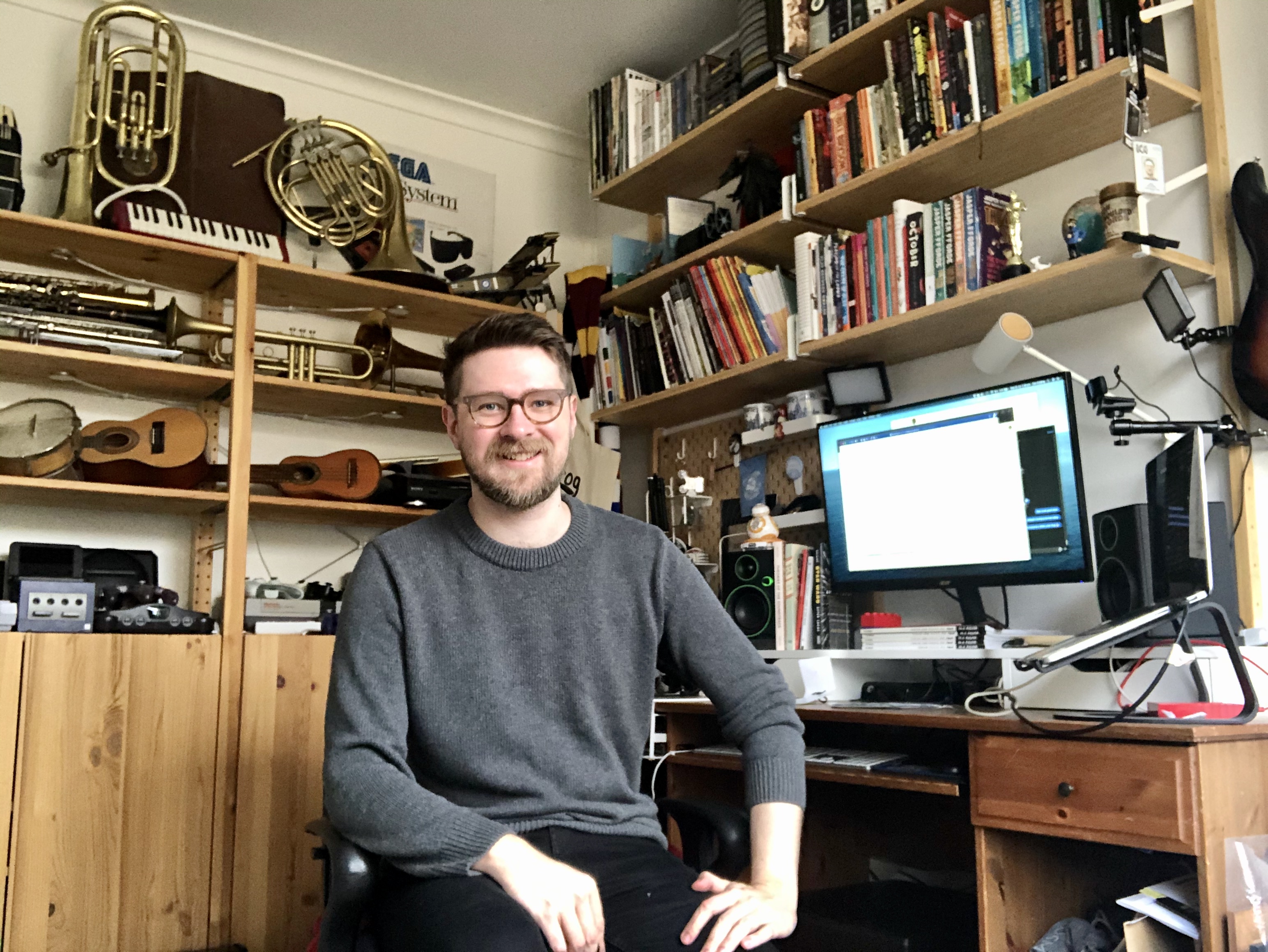 Dr Dan Golding in his home office surrounded by books and musical instruments. 