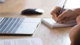 Close up female hands holding pen writing in notepad.