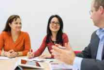 Three people having a work meeting around a desk