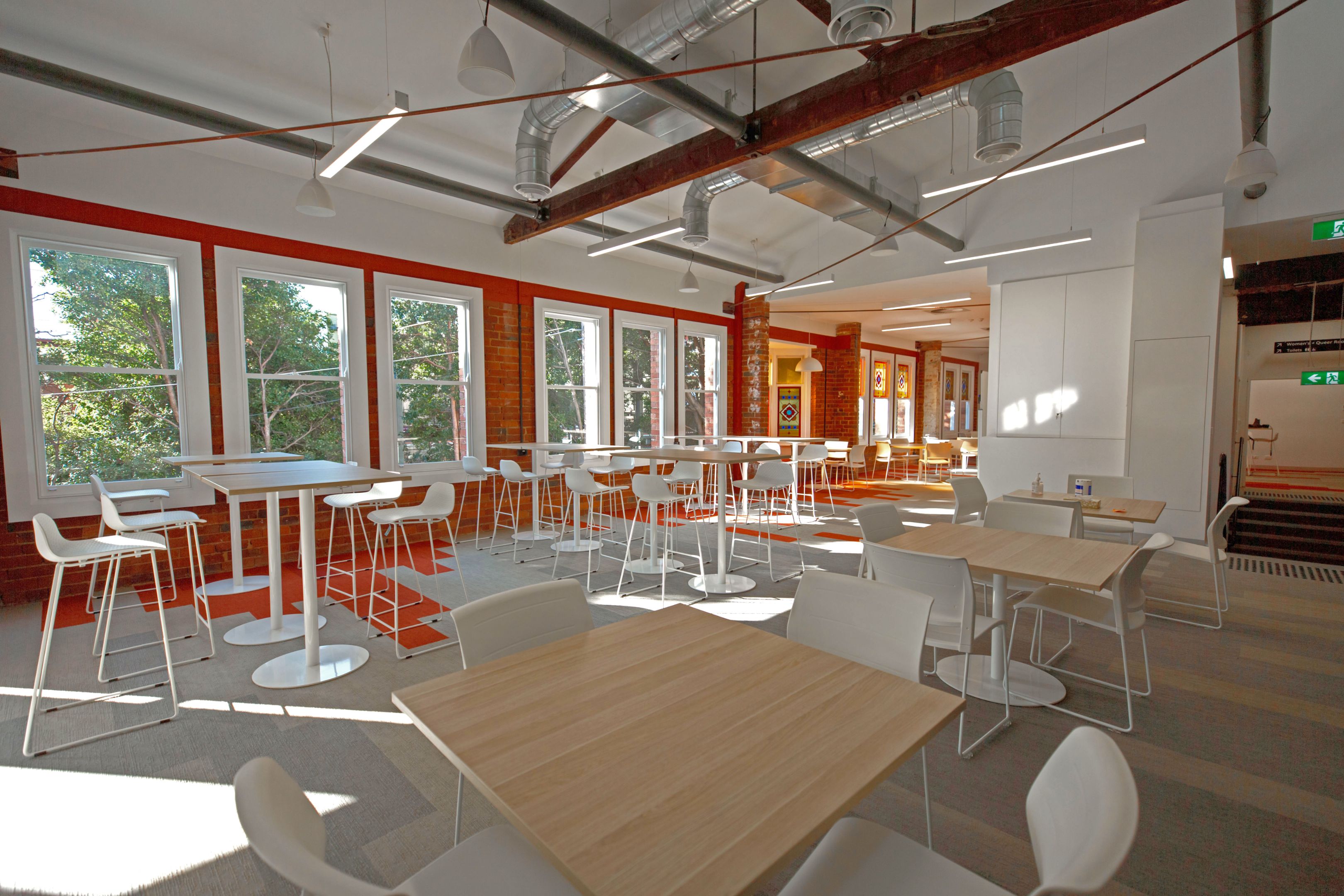 A large open study space, filled with natural light, white chairs and light timber tables