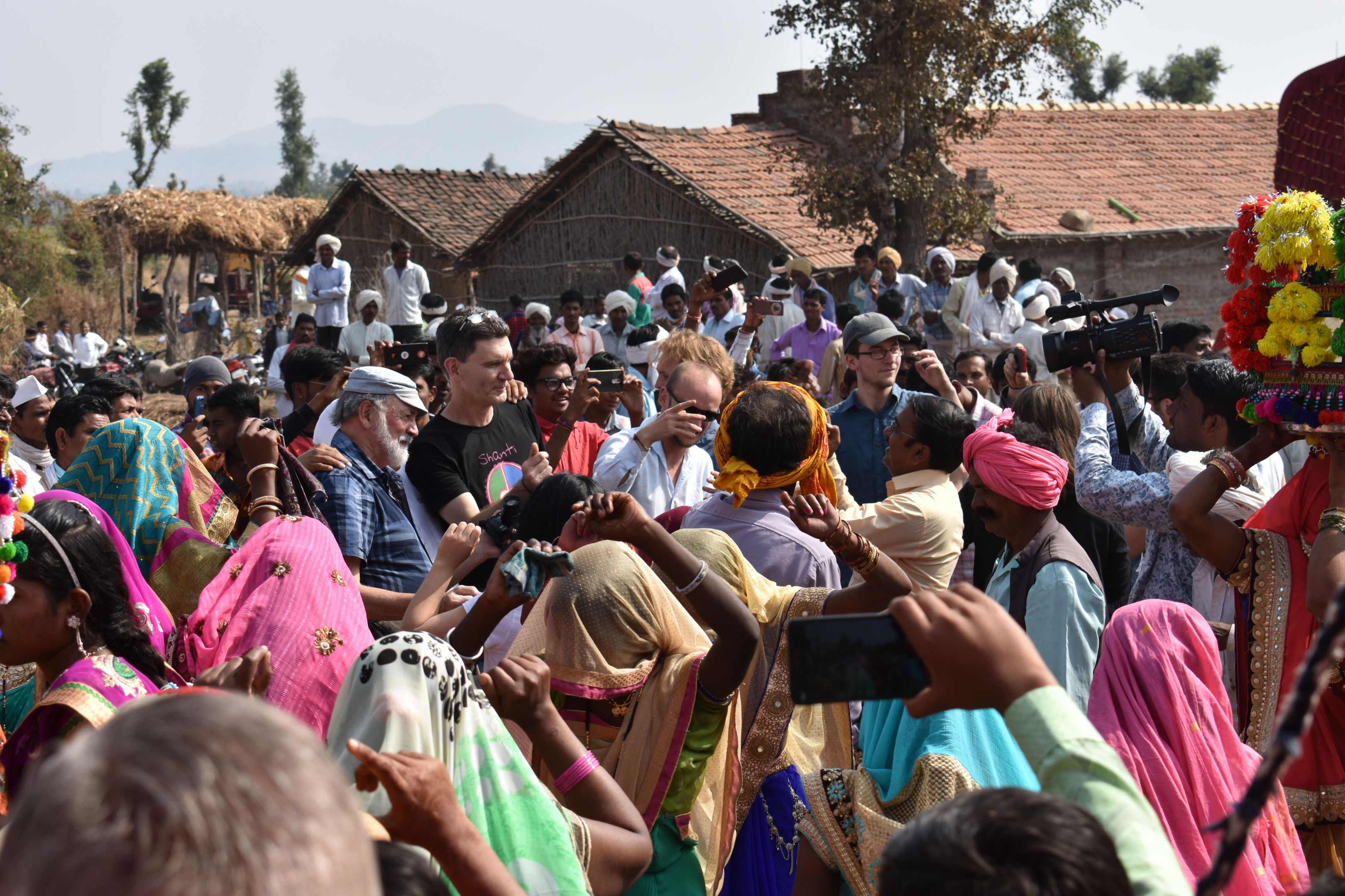 A large group of people gathered around as a crowd taking photos and videos