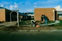 A student uses landscaping machinery to prepare a garden bed