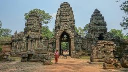 Local woman stands in front of temple ruins