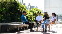 Group of four students sitting at a table outside talking