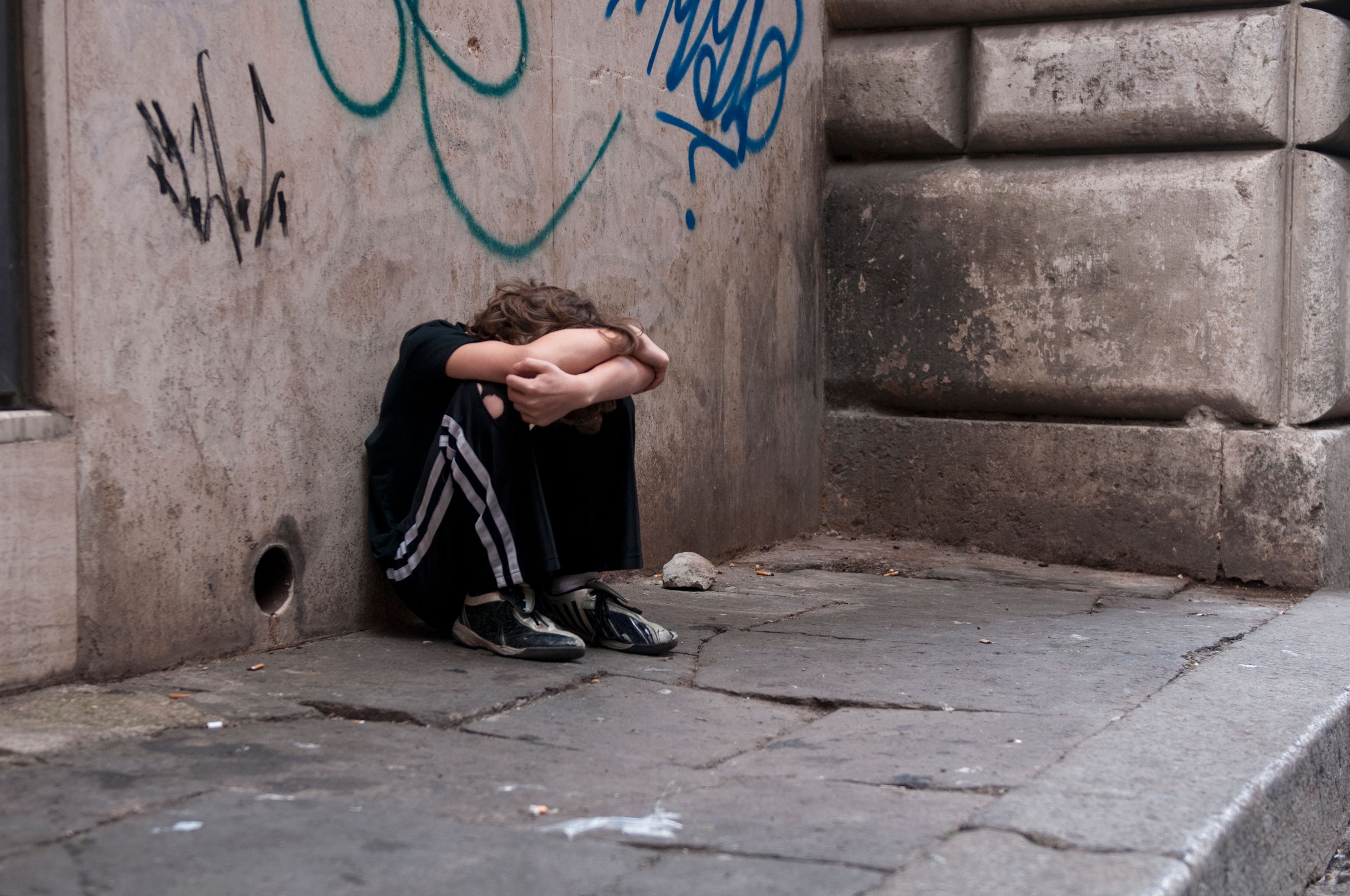 Boy huddled and alone on city street