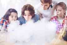 Group of children blowing on fume during chemistry experiment
