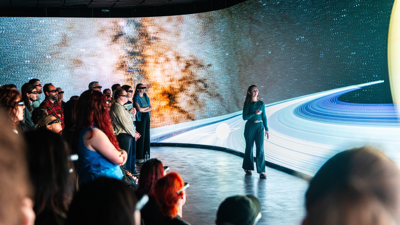 A person in front of a wraparound digital canvas with images of the solar system.