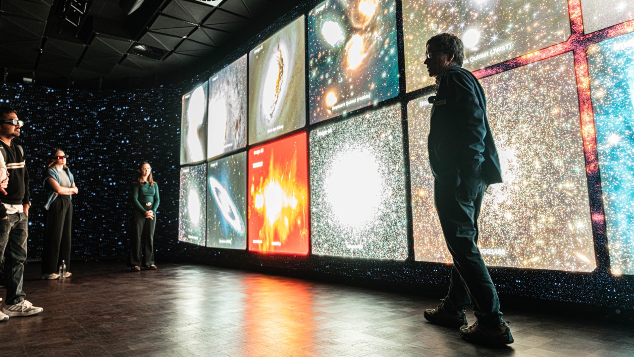 Person standing in front of a stereoscopic LED wall showing images of stars and planets.